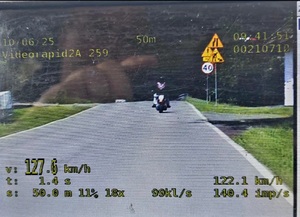 Zdjęcie z wideorejestratora, na którym widać motocyklistę i zarejestrowaną prędkość z jaką sieę poruszał to jest ponad 127 kilometrów na godzinę.