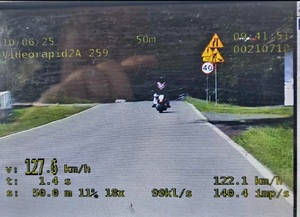 Zdjęcie z wideorejestratora, na którym widać motocyklistę i zarejestrowaną prędkość z jaką sieę poruszał to jest ponad 127 kilometrów na godzinę.