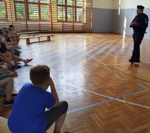 policjant prowadzi prelekcje dla uczniów na sali gimnastycznej