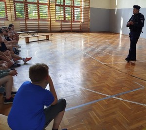 policjant prowadzi prelekcje dla uczniów na sali gimnastycznej
