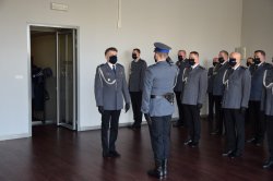 złożenie meldunku Komendantowi Miejskiemu policji w Krakowie w auli, w tle policjanci w strojach galowych
