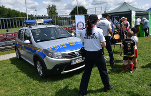 Strażnicy miejscy i pojazd straży miejskiej oraz dzieci biorące udział w akcji