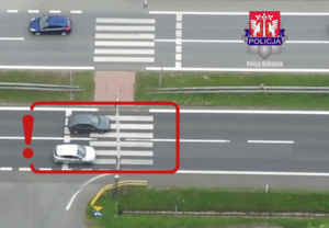 ujęcie z drona pokazujące samochód osobowy wyprzedzający na przejściu dla pieszych