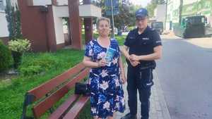 Policjant przekazuje ulotke osobie.