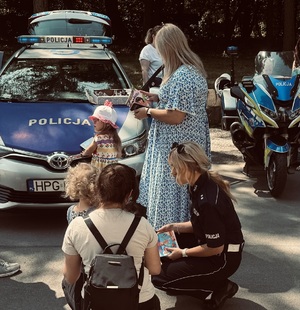 Opiekunka z dzieckiem rozmawiała z policjantką, w tle radiowóz