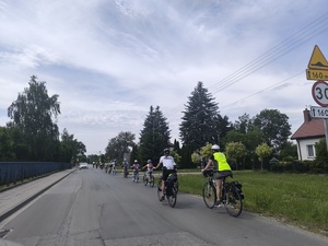 Policjantka na rowerze i opiekun wycieczki jada za kolumną rowerzystów