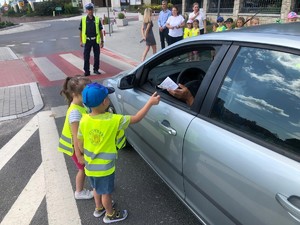 Przedszkolaki wręczają kierujacemu ulotkę informacyjną