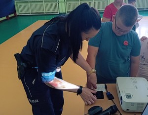 umundurowana policjantka odbija odciski palców chłopcu