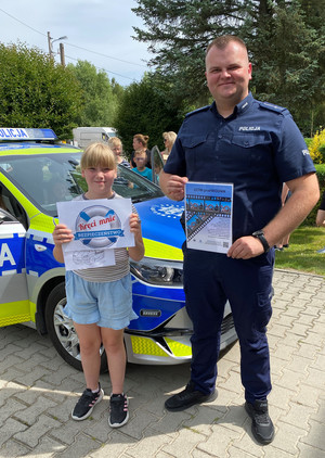 umundurowany policjant z dziewczynką przed radiowozem