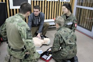 ratownik medyczny uczący resuscytacji trzech uczniów szkoły mundurowej