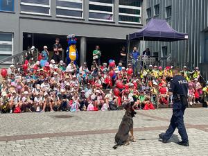 dzieci biorące udział w wydarzeniu oglądają pokaz przygotany przez policyjnego przewodnika psa służbowego