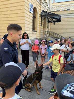 dzieci biorące udział w wydarzeniu stojące przy przewodniku psa służowego oraz psie służbowym