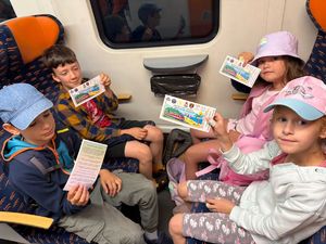 dzieci siedzące w pociągu prezentują pamiątkowe bilety