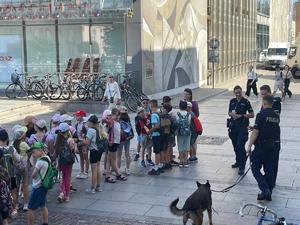 dzieci stojące na placu przed dworcem głónym w towarzystwie policjantów