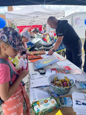 dzieci stojące przy policyjnym stanowisku profilaktycznym.