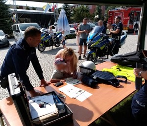 dziecko odbija linie papilarne, w tle pojazdy Policji