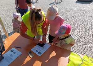 policjantka pomaga dziewczynkom odbić linie papilarne na pamiątkowym dyplomie