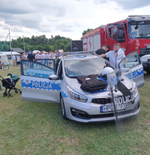 Oznakowany radiowóz oraz wóz strażacki. Na zdjęciu widoczne osoby biorące udział w akcji
