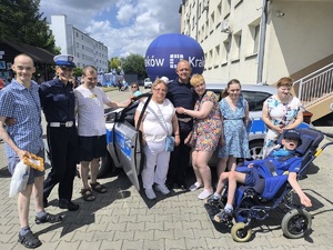 policjanci przy radiowozie pozują do wspólnego zdjęcia z uczestnikami festynu