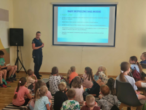 policjantka wyjaśnia dzieciom zasady bezpieczeństwa nad wodą