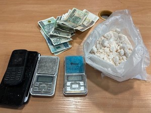 biały prosze w foliowym worku, telefony komórkowe, wagi elektorniczne oraz gotówka ułożone na stole