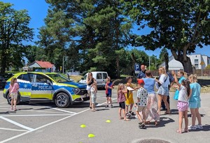 Policjant prezentuje dziecion oznakowany radiowóz