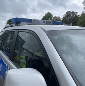 zdjęcie boku policyjnego radiowozu z kroplam,i deszczu