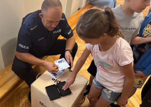 dzieci odpijają odciski swoich dloni na pamiątkowych kartach z numerem alarmowym