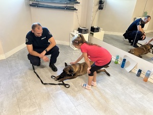 dziewczynka głaszcze psa służbowego w towarzystwie policjanta