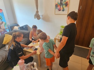 policjantka pomaga dziecku odbić palce na pamiątkowej karcie