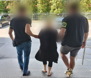 policjanci prowadzą kobietę w kajdankach po schodach
