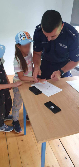 Umundurowany policjant oraz dziecko podczas pokazu zbierania odcisków palców