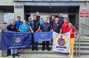 Wspólne zdjęcie uczestników spotkania przed budynkiem Komendy Miejskiej Policji w Nowym Sączu.