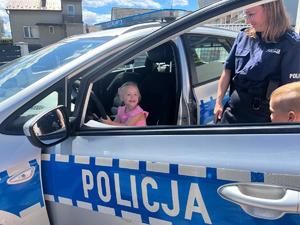 Dziewczynka siedząca w radiowozie, obok policjanta