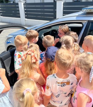 Policjantka z przedszkolakami przy radiowozie