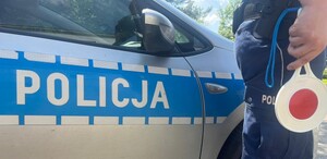 Policjant trzymający tarczę do zatrzymywania na tle radiowozu