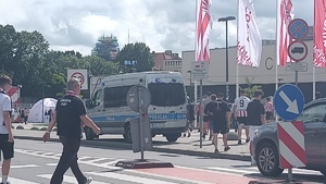 kibice w trakcie dojścia na stadion przy ul. Kazłuży. Na chodniku widać zaparkowany radiowóz