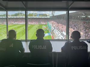 trzech policjantów na stanowisku dowodzenia obserwuje sytuację na stadionie