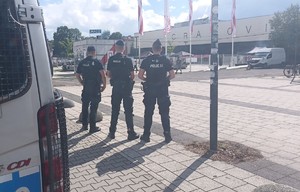 trzech umundurowanych policjantów stojacych przy radiowozie obserwujacych stadion Cracovii