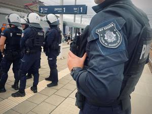 umundurowani policjanci na peronie kolejowym obserwują kibiców wsiadających do pociągu