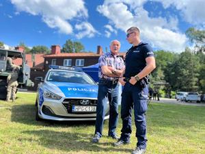 policjant stojący przy radiowozie z seniorem