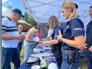 policjantki z seniorem rozmawiający przy stoisku profilaktycznym