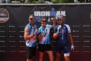 troje policjantów biorących udaił w zawodach Ironman pozują na ściance z medalami