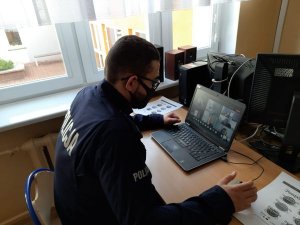 1.Umundurowany policjant przed laptopem podczas lekcji on-line
