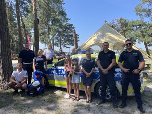 uczestnicy przy radiowozie z policjantami