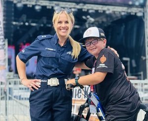 policjantka pozuje do zdjęcia z chłopcem, w tle scena