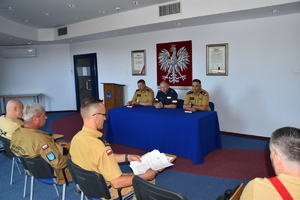 Przy stole na auli siedzi komendant powiatowy policji  i  2 komendantów ze straży pożarnej