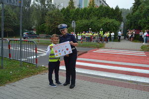 Policjanka wraz z dzieckiem trzymają w ręku plakat