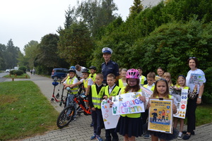 Policjant wraz z dziećmi ubranymi w kamizelki odblaskowe