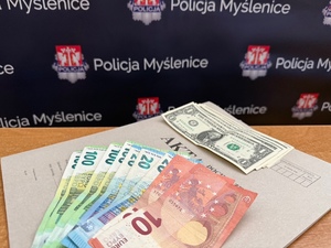 banknoty w obcychy walutach na tle napisów PolicjaMyślenice